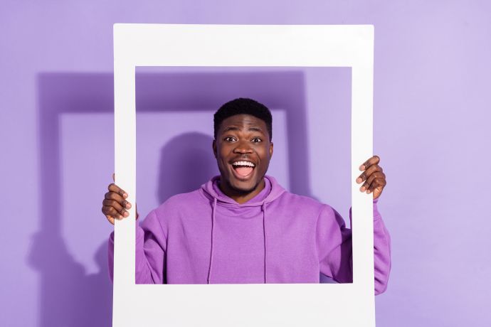 young man standing inside a frame that he is holding