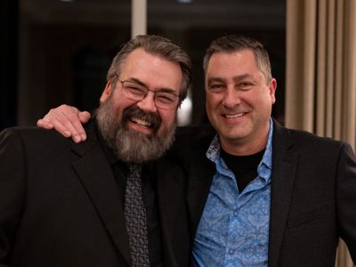 Two men posing for the camera at a holiday party
