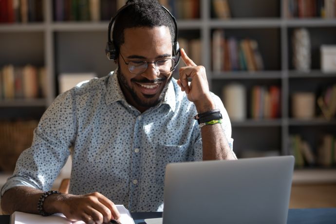 Focused African man sitting at desk wear headset . Manager talk to client provide professional help and support concept