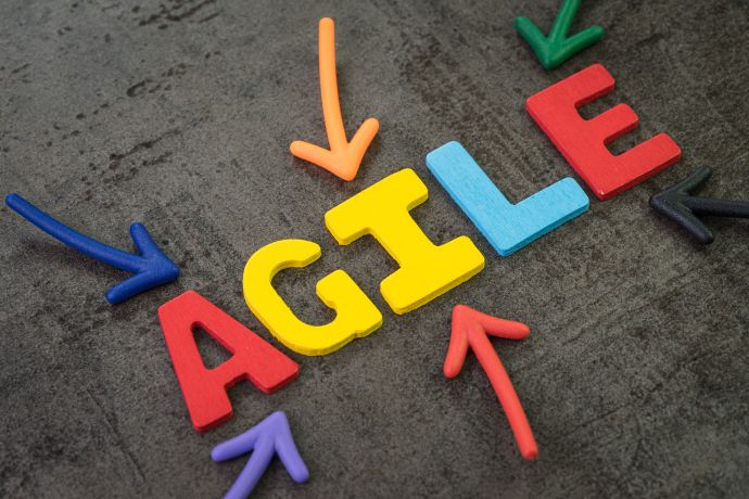  multi color arrows pointing to the word AGILE at the center of black cement chalkboard wall